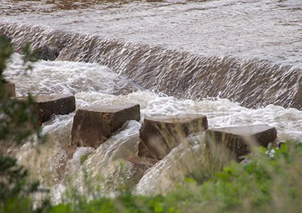 A turbid, muddy rushing stream of overflowing river water
