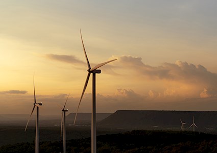 Windmill farm on mountain with sunset sky