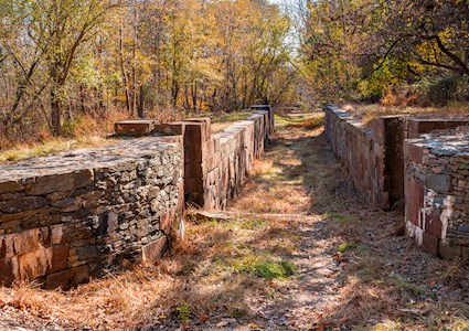 An abandoned canal with overgrown grass and brush. 