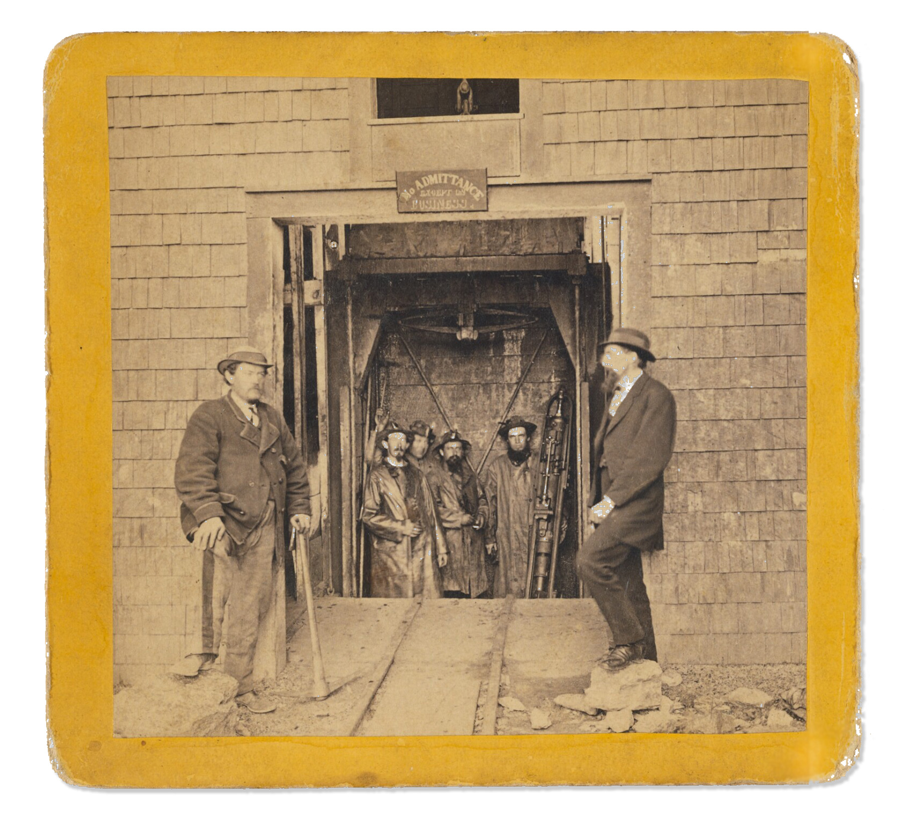 Men stand on a platform that descends into a shaft.