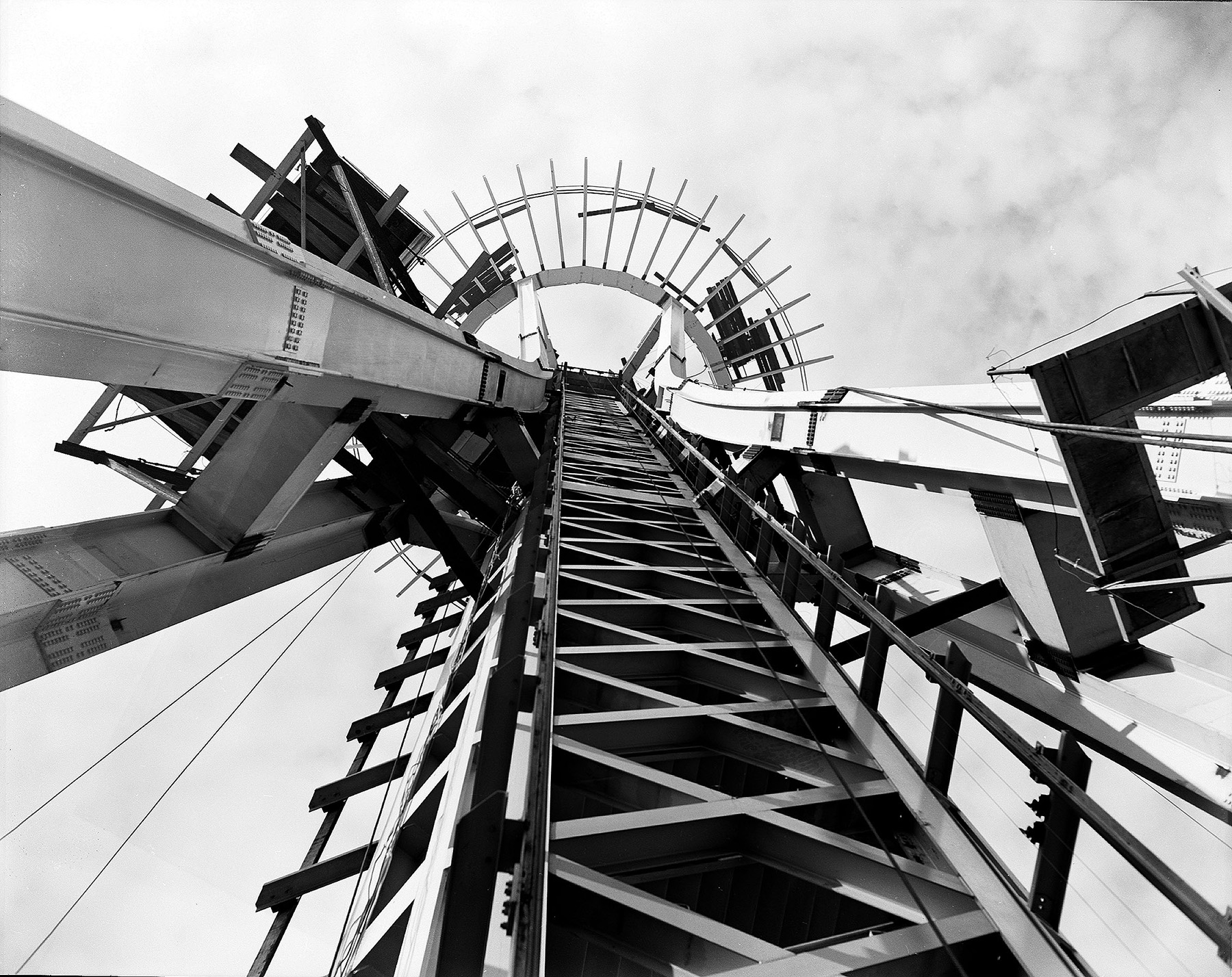 The photograph shows a tall structure with long thin, steel columns connected to a central core