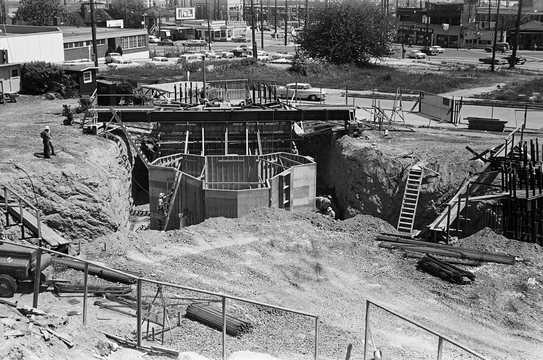 The photograph shows a large hole in the ground. There is the beginning of a y-shaped steel structure being built.