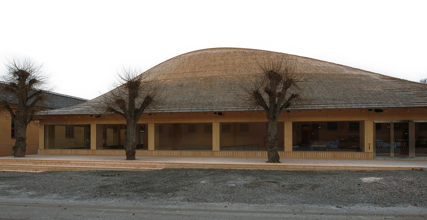 An exterior view of the building highlights the undulating form of the shingled roof.