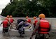 people wearing life vests push a boat with a motor up a hill on a flooded highway