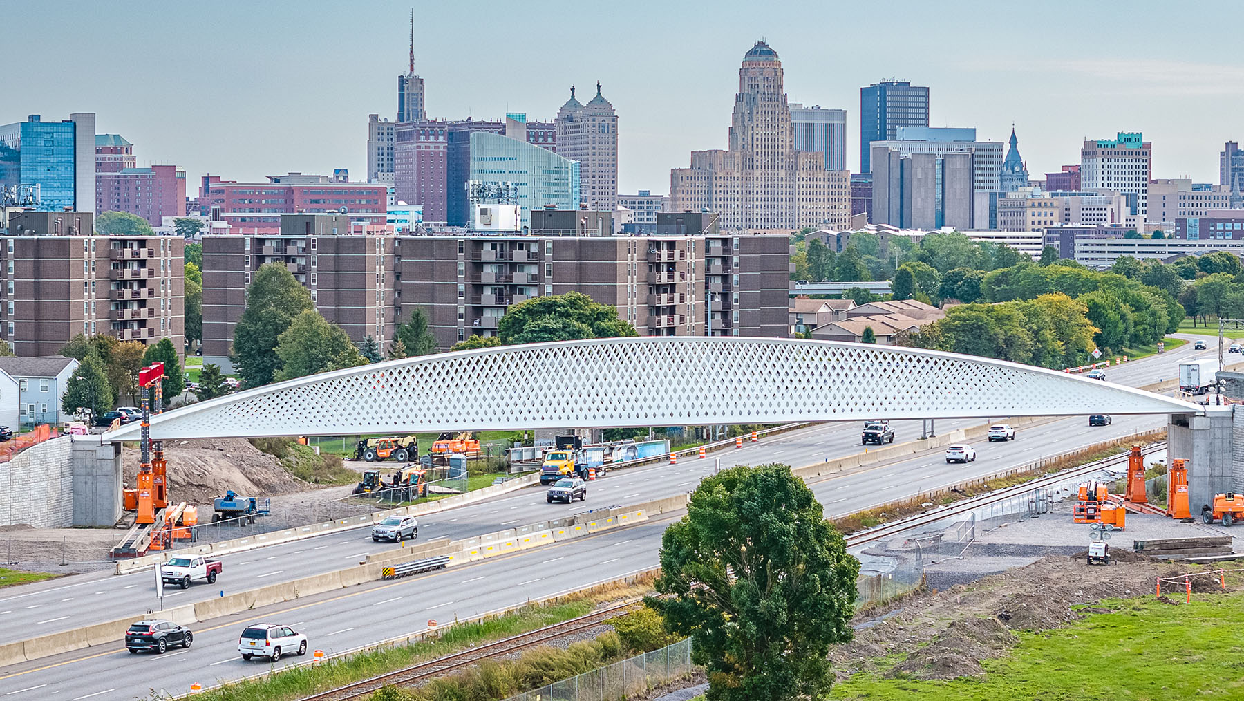 a pedestrian bridges spans an interstate with a city skyline in the background a pedestrian bridges spans an interstate with a city skyline in the background